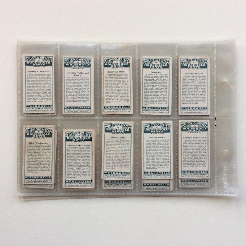 May include: A collection of vintage Wills Cigarettes Household Hints cards, presented in a clear plastic holder. Each card has text and a blue border. The cards are arranged in rows, offering household tips.