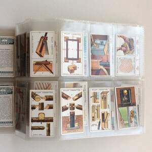 May include: A selection of vintage Wills's Cigarettes cards, held in a clear plastic display. The cards depict illustrations of carpentry tools and methods, with text including "Rustic Work" and "Broken Line".