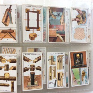 May include: A set of vintage Wills's Cigarettes cards, showcasing illustrations related to carpentry and woodworking. The cards display different stages of construction, such as making picture frames and rustic work. The text "WILLS'S CIGARETTES" is printed on each card.