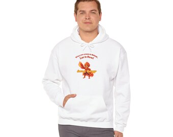 Puede incluir: Una sudadera blanca con capucha que presenta un gráfico de una criatura naranja ardiente con el texto "What you create is MAGIC. Let it flow!" y "Sacral Energy" impreso en rojo y amarillo en el centro del pecho.