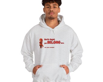 Puede incluir: Una sudadera con capucha gris claro que presenta un gráfico de una pequeña criatura roja y el texto Earth Angel, you BELONG here. THE ROOT BUDDY. La sudadera incluye un bolsillo tipo canguro frontal, mangas largas y capucha.