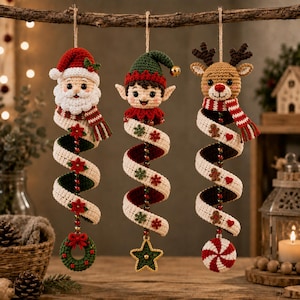 May include: Three hanging crochet ornaments featuring a Santa Claus, an elf, and a reindeer. Each figure has a long, spiralling cream-coloured body decorated with small festive motifs like poinsettias, snowflakes, gingerbread men, and hearts.