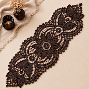 May include: A dark brown, elongated crochet table runner featuring an intricate, repeating floral and leaf pattern with scalloped edges. The lace design is composed of interconnected circular motifs and pointed petal shapes, creating a detailed openwork texture.