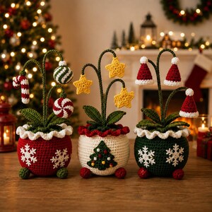 Può includere: Tre piante in vaso realizzate all'uncinetto con temi festivi. Il vaso rosso ha decorazioni a forma di bastoncino di zucchero, quello bianco stelle gialle e quello verde cappellini di Babbo Natale. Ogni vaso ha foglie verdi e un bordo bianco.