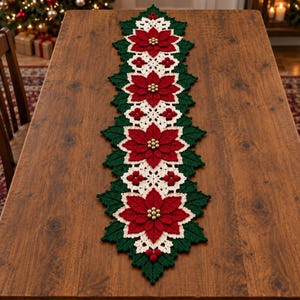 Pode incluir: Um caminho de mesa de crochê longo e retangular com um padrão repetitivo de flores de poinsétia vermelhas com centros de contas douradas, rodeadas por folhas verde-escuras e seções de renda creme com pequenos cachos de bagas vermelhas.