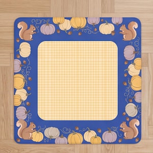 May include: A square mat featuring a central light yellow gingham pattern bordered by a deep blue frame. The border is decorated with illustrations of brown squirrels, various pumpkins in shades of orange, yellow, and purple, and small brown acorns.