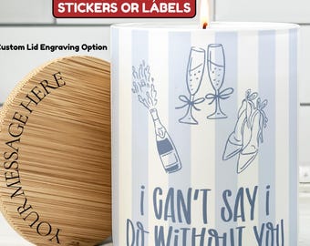 May include: A white candle with blue vertical stripes and the text "I CAN'T SAY I DO WITHOUT YOU." The candle has illustrations of champagne glasses, a bottle, and shoes. A wooden lid with custom engraving is next to the candle.