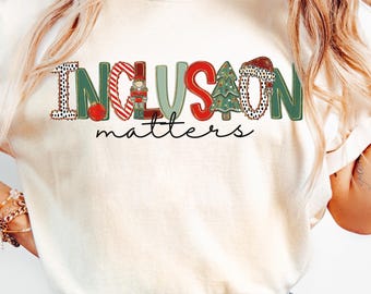 May include: Cream-coloured t-shirt with the words "INCLUSION matters" in a festive, colourful design. The word "INCLUSION" features a mix of patterns and holiday-themed elements. The shirt is available in long sleeve and sweatshirt styles.