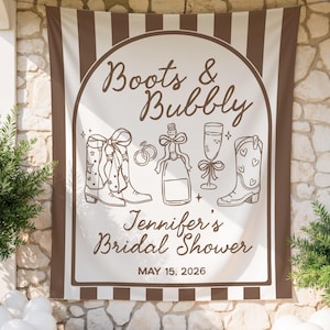 Puede incluir: Una pancarta beige y marrón con el texto "Boots & Bubbly" y "Jennifer's Bridal Shower" con ilustraciones de botas de vaquero, champán y una copa de champán. También se muestra la fecha "15 de mayo de 2026".