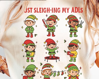 May include: Cream-colored long-sleeve shirt with a graphic of nine cartoon elves in green and red outfits. The elves are engaged in various activities. Text at the top reads "ALSO IN LONG SLEEVE AND SWEATSHIRT" and "JUST SLEIGH-ING MY ADLS".