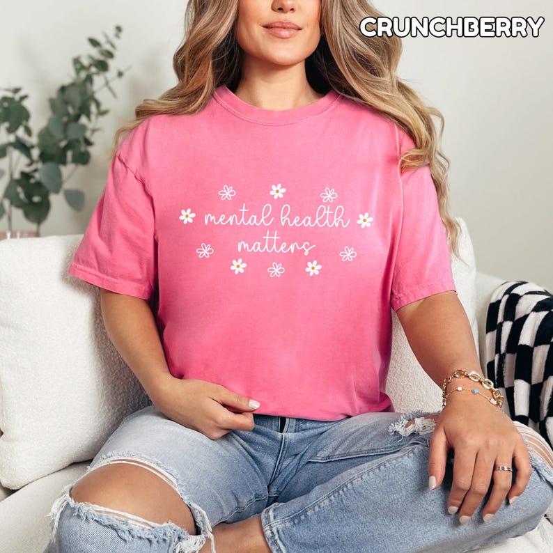 May include: A pink t-shirt with the text "mental health matters" in white lettering and a white daisy pattern around the text.