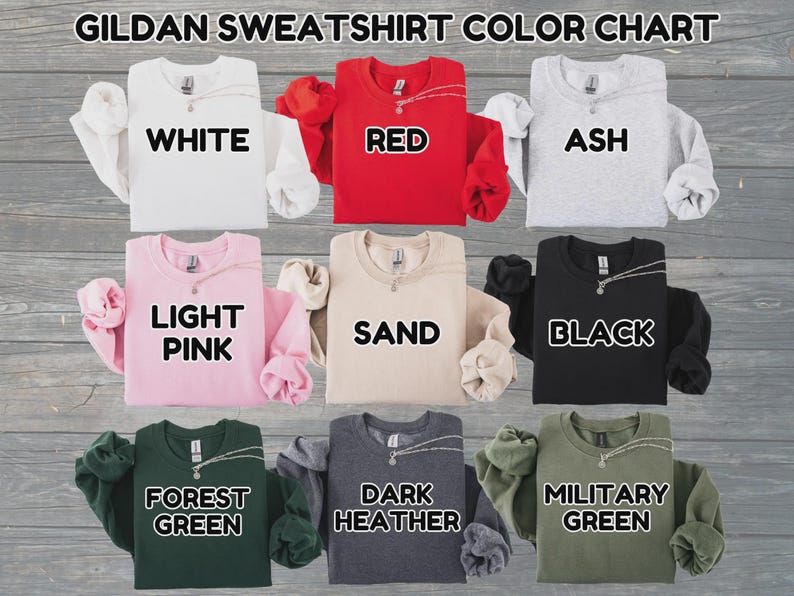 May include: Gildan sweatshirt color chart featuring nine crewneck sweatshirts in white, red, ash, light pink, sand, black, forest green, dark heather, and military green. Each sweatshirt is labeled with its corresponding color name.