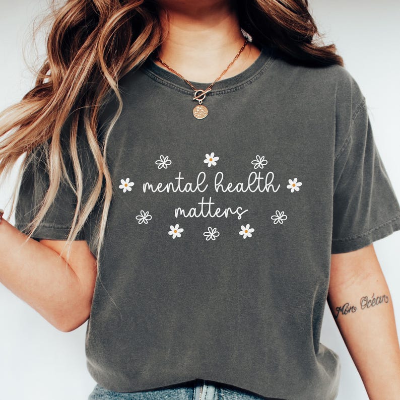 May include: A dark gray t-shirt with the text "mental health matters" in white lettering and a daisy pattern around the text.