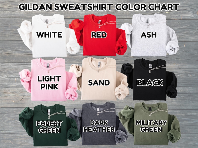 May include: A color chart displaying Gildan sweatshirts in various colors. The colors include white, red, ash, light pink, sand, black, forest green, dark heather, and military green. Each sweatshirt has a necklace.