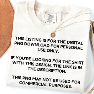 May include: Cream-colored t-shirt with text: "THIS LISTING IS FOR THE DIGITAL PNG DOWNLOAD FOR PERSONAL USE ONLY. IF YOU'RE LOOKING FOR THE SHIRT WITH THIS DESIGN, THE LINK IS IN THE DESCRIPTION. THIS PNG MAY NOT BE USED FOR COMMERCIAL PURPOSES." A gold necklace is draped on the shirt.