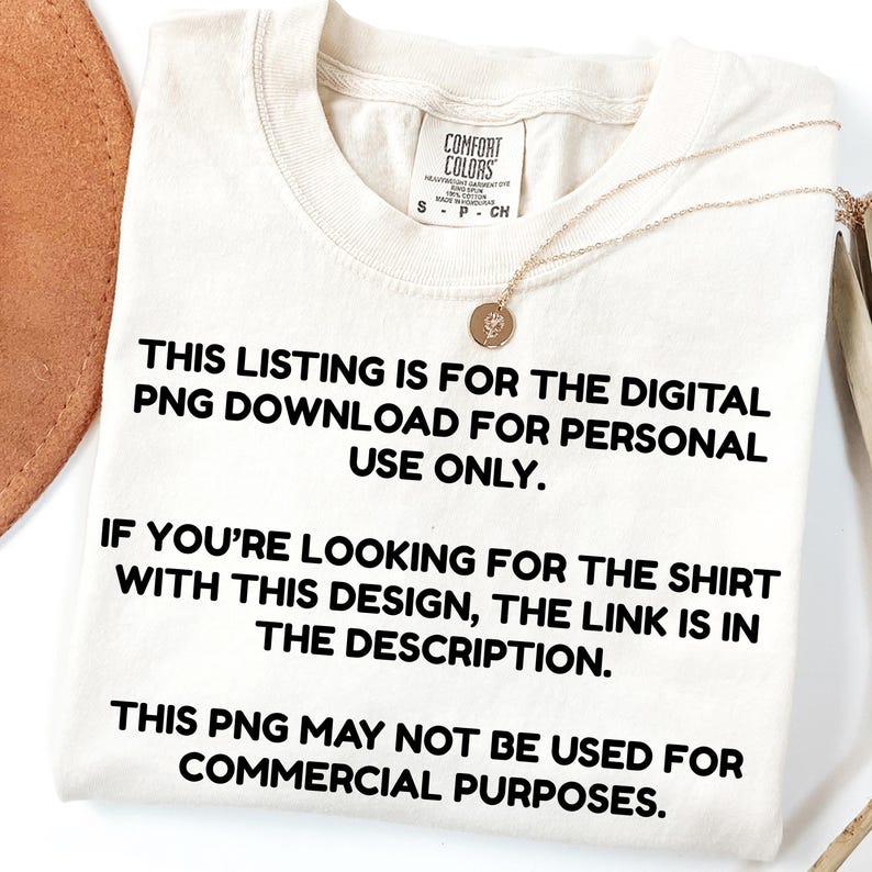 May include: Cream-colored t-shirt with text: "THIS LISTING IS FOR THE DIGITAL PNG DOWNLOAD FOR PERSONAL USE ONLY. IF YOU'RE LOOKING FOR THE SHIRT WITH THIS DESIGN, THE LINK IS IN THE DESCRIPTION. THIS PNG MAY NOT BE USED FOR COMMERCIAL PURPOSES." A gold necklace is draped on the shirt.