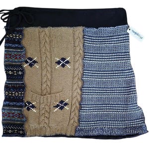 Op de afbeelding: Een patchwork rok met een zwarte tailleband en trekkoord. De rok heeft delen van kabelgebreide, patroon gebreide en gestreepte gebreide stoffen in tinten bruin, blauw en marine. Een label met "mojowear" is bevestigd.