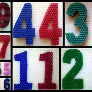 May include: Assortment of colorful honeycomb number candles, including yellow, red, green, blue, and purple. The numbers range from 0 to 9.