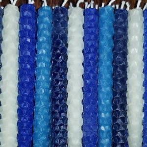 May include: A collection of blue and white honeycomb candles. The candles are arranged in a row and are all the same size. The candles are made of beeswax and have a natural, rustic look.