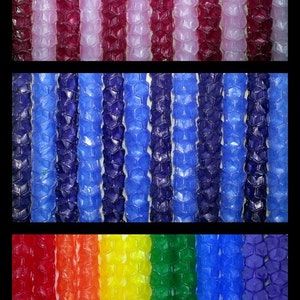May include: A close-up of a variety of colorful, textured, honeycomb-shaped candles. The candles are arranged in three rows, with the top row being pink and red, the middle row being blue and purple, and the bottom row being red, orange, yellow, green, blue, and purple.