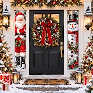 May include: A black front door decorated with a large evergreen wreath featuring red berries, pinecones, and a prominent red bow. Two vertical banners hang on either side, one depicting Santa Claus and the other a snowman, surrounded by holiday lights.
