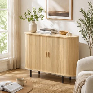 May include: A light wood sideboard with a rounded, tambour-style slatted front and two central doors featuring vertical wooden handles. The cabinet is supported by four thin, black cylindrical legs and has a smooth, flat top surface.