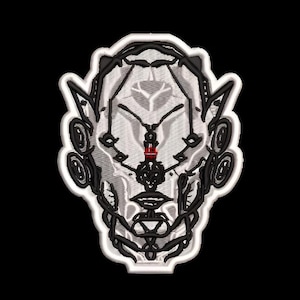 Puede incluir: Un parche bordado que presenta un diseño de rostro estilizado y simétrico en tonos blanco, gris y negro. La figura tiene líneas intrincadas, detalles circulares en las orejas y un pequeño acento rojo vibrante en el puente central.