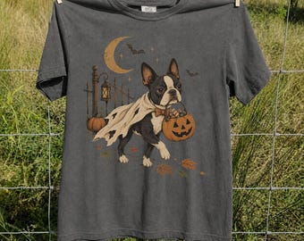 May include: A charcoal gray short-sleeve t-shirt featuring a graphic of a Boston Terrier wearing a ghost cape and a bow tie. The dog carries a jack-o'-lantern bucket. The design includes a crescent moon, bats, a fence, and autumn leaves.