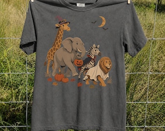 May include: A charcoal gray short-sleeve t-shirt featuring a graphic of a giraffe in a witch hat, an elephant holding a jack-o'-lantern, a zebra, and a lion wearing a ghost costume, all surrounded by orange pumpkins and a crescent moon.