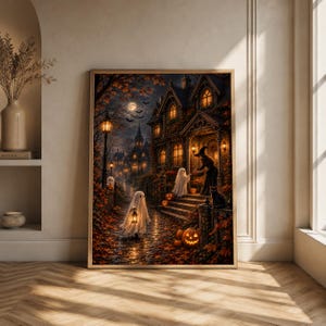 May include: A framed wall art print depicting a nighttime Halloween scene with a dark gothic house, a witch standing on the porch, two figures dressed as ghosts holding lanterns, a black cat, and several glowing orange jack-o'-lanterns.