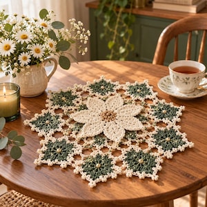 May include: A round, crocheted doily featuring a central cream-colored flower motif surrounded by dark green, star-shaped segments. The design is accented with small, light-colored beads integrated into the dark green sections and the center of the flower.