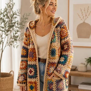 Pode incluir: Um cardigã com capuz e mangas compridas feito de quadrados de crochê multicoloridos em tons de azul, laranja, amarelo e roxo, unidos por uma borda de fio bege claro, com dois bolsos frontais e um design de frente aberta.