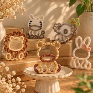 May include: A collection of small, handcrafted animal-shaped ornaments made from woven cord. The figures include a bear, a lion, a zebra, a koala, and a rabbit, each featuring distinct color patterns and textures in shades of brown, white, and tan.