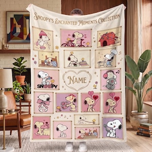 May include: A cream-colored fleece blanket titled Snoopy's Enchanted Moments Collection, featuring a grid of various Snoopy illustrations in pink and brown frames, including Snoopy skating, cycling, and holding balloons, with a central heart for a name.