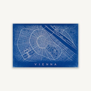 May include: A rectangular print featuring a detailed white line map of Vienna on a deep blue background. The map displays the city's street grid, river, and park layouts. The word VIENNA is printed in white capital letters at the bottom center.