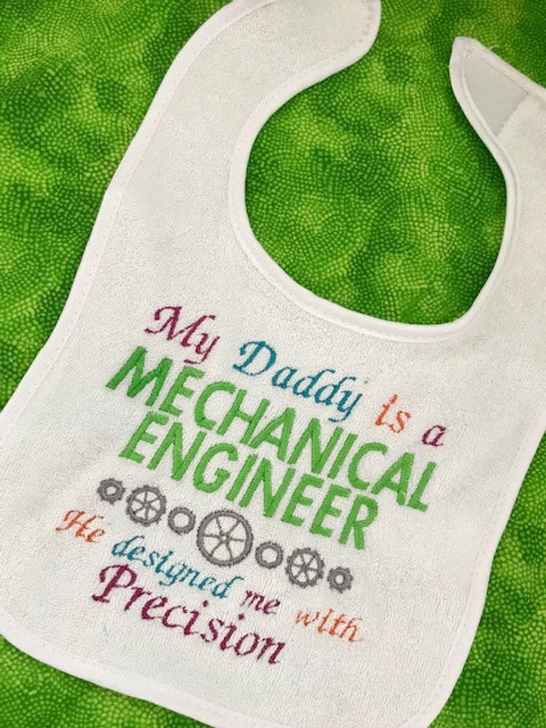 Puede incluir: Babero blanco para beb&eacute; con texto bordado de colores que dice "Mi pap&aacute; es un ingeniero mec&aacute;nico. Me dise&ntilde;&oacute; con precisi&oacute;n."