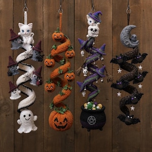 May include: Four hanging crochet decorations featuring Halloween themes. The first is a white spiral with ghosts and a cat. The second is an orange spiral with pumpkins. The third is a purple spiral with a cauldron, skulls, and a cat. The fourth is a dark brown spiral with bats and a moon.
