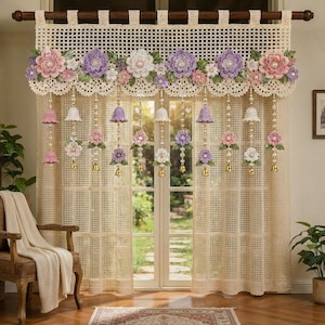 May include: A cream-colored crochet curtain featuring a valance with large, three-dimensional pink, purple, and white floral appliqués. Hanging from the valance are multiple vertical strands adorned with small crochet flowers, beads, and tiny gold bells.
