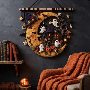 Può includere: Una decorazione da parete a forma di mezzaluna all'uncinetto gialla con un volto, un cappello da strega viola, una casa scura, fantasmi bianchi, zucche arancioni e stelle appese, sospesa a un bastone di legno con dettagli in filo nero.