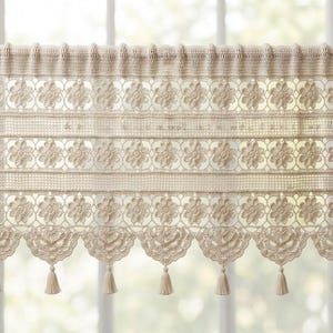 May include: A cream-colored crochet valance curtain featuring horizontal bands of floral motifs, a solid top header for rod insertion, and a bottom edge finished with scalloped crochet patterns and hanging tassels along the lower border.