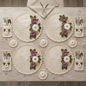 May include: A set of four round cream-colored crocheted placemats, each featuring a side arrangement of crocheted white daisies, purple flowers, and green leaves. Includes four matching rectangular utensil holders and four small round coasters.