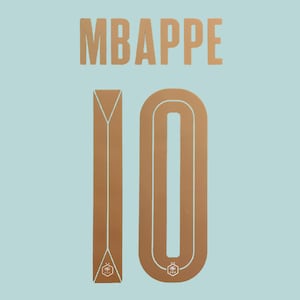May include: A light blue background featuring the name MBAPPE in large, metallic gold block letters. Below the name is the number 10 in a matching metallic gold, with a small, intricate emblem printed at the base of both the one and the zero.