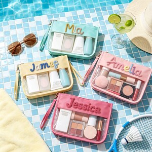 Puede incluir: Cuatro estuches rectangulares con cremallera en color menta, amarillo, rosa y rosa oscuro, cada uno con un panel frontal transparente y un nombre bordado en letras afelpadas: Mia, James, Amelia y Jessica. Contienen diversos cosméticos.