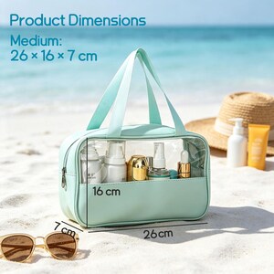 Puede incluir: Un neceser de color verde menta con panel frontal transparente, dos asas superiores y cierre de cremallera. El texto indica Product Dimensions Medium 26 x 16 x 7 cm, con etiquetas que se&ntilde;alan las medidas de 26 cm de largo, 16 cm de alto y 7 cm de fondo.