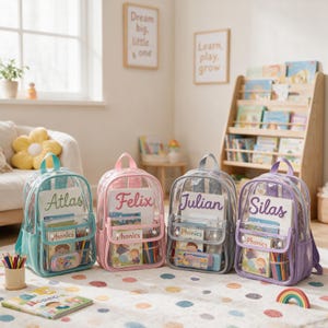 Peut inclure: Quatre sacs à dos transparents en bleu clair, rose, gris et violet, chacun avec une poignée, une poche avant et un prénom brodé en écriture cursive : Atlas, Felix, Julian et Silas. Chaque sac contient des livres et des crayons.