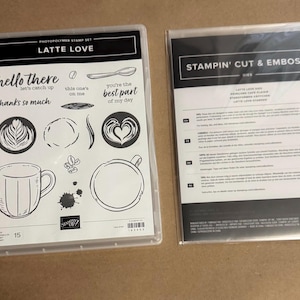 May include: A Latte Love photopolymer stamp set in a clear plastic case featuring coffee-themed illustrations like mugs, coffee beans, and text phrases including hello there, let's catch up, and you're the best part of my day, next to a die set.