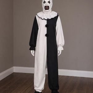 Peut inclure: Un costume de clown complet comprenant une combinaison bicolore noire et blanche avec un col à volants et deux pompons noirs. L'ensemble inclut un masque de clown blanc avec du maquillage noir, un petit chapeau haut-de-forme et des chaussures noires.