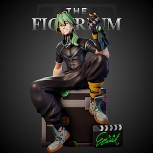 May include: A stylized figurine of a character with green hair, wearing a black shirt and pants with yellow leg wraps and light-colored boots. The character sits on a black box with circular stickers, next to a black clapperboard with green text.
