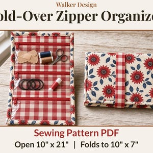 Op de afbeelding: Een Walker Design Fold-Over Zipper Organizer naaipatroon PDF. De organizer heeft een rood-wit geblokte binnenkant met drie doorzichtige ritsvakken en een zonnebloemprint aan de buitenkant. De afmetingen zijn 25,4 cm bij 53,3 cm wanneer open.