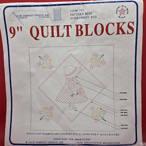 May include: A white package of 9 inch quilt blocks by Jack Dempsey Needle Art featuring the Sunbonnet Sue pattern. The front shows a line drawing of a girl in a bonnet holding flowers, surrounded by floral motifs, with DMC color codes listed.